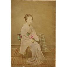 Japanese woman seated holding fan.