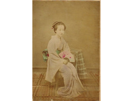 Japanese woman seated holding fan.