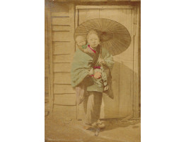 Japanese woman with child and umbrella, in front of wooden door.