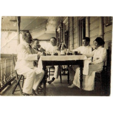 Men and native woman drinking on verandah at Lavinia's hotel.