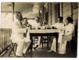 Men and native woman drinking on verandah at Lavinia's hotel.